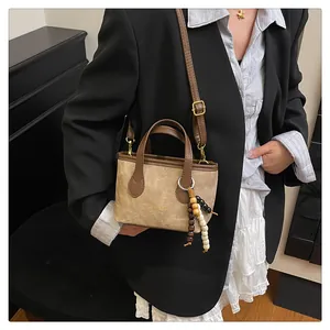 Detail of beige suede mini tote with brown handles and three-color wooden bead charm