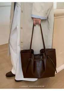 Close-up of vintage brown leather tote bag showing side drawstring detail and texture