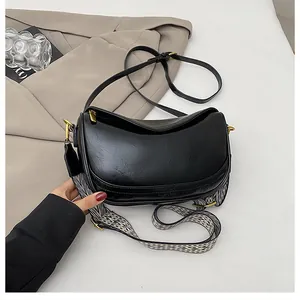 Detail view of black crescent moon bag with textured leather and checkered shoulder strap