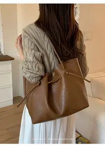 Detail of caramel brown tote bag with decorative knot on minimalist leather strap