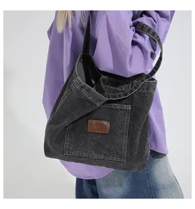 Detail of dark grey denim tote bag showing the textured fabric and leather logo patch