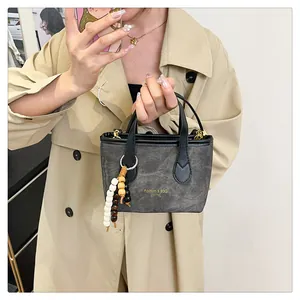 Detail of dark gray canvas tote bag with black leather straps and beaded charm