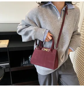 Mannequin portant un sac cabas bordeaux en daim avec fermoir argenté et bandoulière
