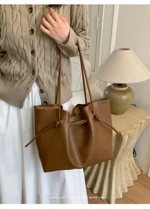 Detail of minimalist brown tote bag with side drawstring knot and soft faux leather texture