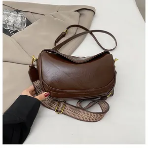 Detail of dark brown crescent bag with pleated texture and adjustable double straps