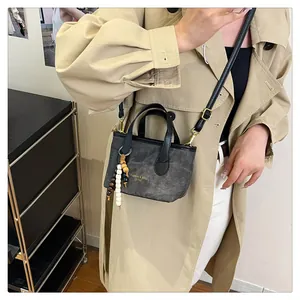 Detail of dark grey canvas bucket bag with beaded charm and adjustable strap