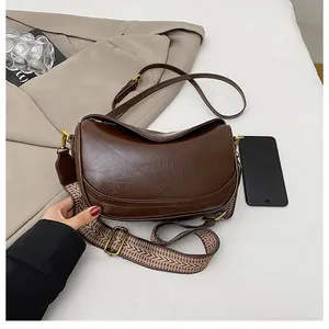 Detail of dark brown retro half-moon bag with woven strap and vintage metal hardware