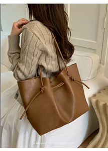 Close-up of retro brown leather tote bag with unique knot details on the shoulder strap