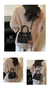 Detalle del bolso de ante negro con diseño de hebilla y mini colgante marrón