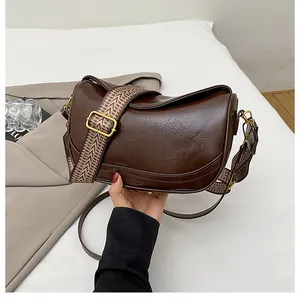Detail of brown retro embossed crescent bag with ethnic fabric and leather straps