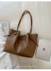 Detailed top view of brown leather tote bag with knotted drawstring handle and iPad for scale