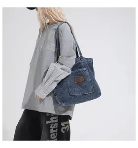 Detail view of washed denim tote bag with front pocket and brown leather logo patch