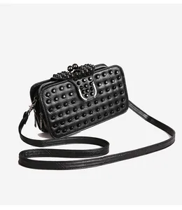 Detail of black studded crossbody bag with silver horseshoe buckle and punk aesthetics