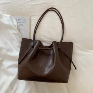 Detail of dark brown tote bag showing smooth oil-wax texture and drawstring closure