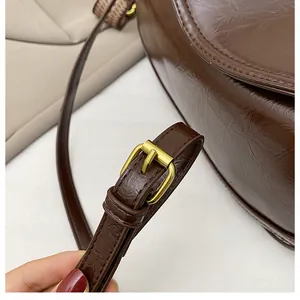 Detail of dark brown leather shoulder strap with adjustable golden buckle and glossy finish