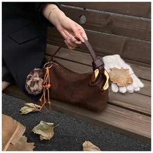 Detail of vintage brown suede handbag featuring chunky gold metal rings and leopard charm