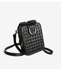 Close-up of black rivet-decorated mini crossbody bag with silver U-shaped metal buckle