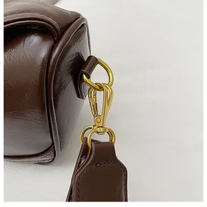 Close-up of golden metal lobster clasp and D-ring on brown vintage leather bag