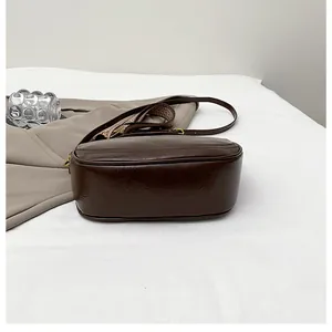 Detail of dark brown retro crossbody bag with textured leather and patterned woven strap