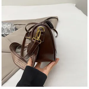 Close-up of a vintage brown leather dumpling bag with woven strap and gold metal buckle