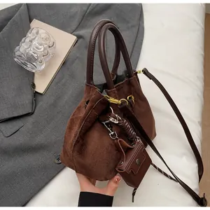 Bolso saco de ante marrón oscuro con herrajes dorados y mini colgante a juego