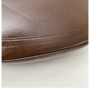 Detail of brown pleated leather texture and embossed logo on the vintage crossbody bag