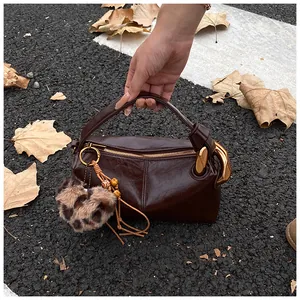 Detail of dark brown leather handbag with gold metal clasp and leopard heart charm