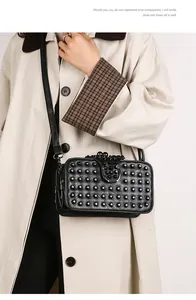 Detailed view of punk style black leather crossbody bag with metallic rivet embellishments