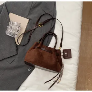 Detalle de bolso tipo cubo marrón mate con cinta de cuadros, cuentas y monedero mini