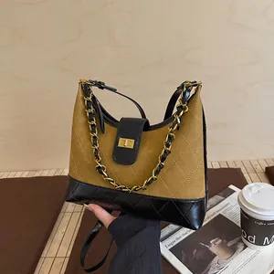 Λεπτομέρεια καφέ καπιτονέ τσάντας με χρυσή αλυσίδα και μεταλλικό κούμπωμα ασφαλείας