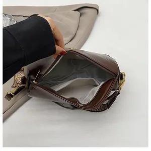 Detail view of brown leather crossbody bag interior with zip pocket and woven strap