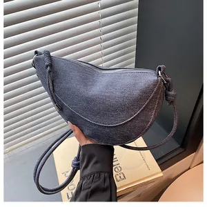 Λεπτομέρεια τσάντας μισοφέγγαρο από denim με μεταλλικό φερμουάρ και λουράκι με κόμπους