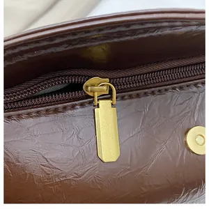 Detail of dark brown vintage textured leather bag with gold zipper and magnetic buckle