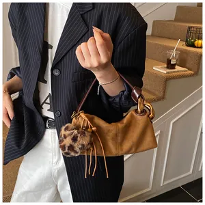 Detail of vintage brown suede handbag featuring leopard pom-pom and leather tassels