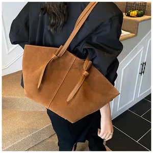 Détail de la texture en daim et du nœud décoratif sur la bandoulière du sac marron
