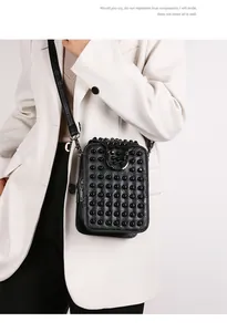 Close-up of black rivet-studded handbag with matte leather finish and silver buckle
