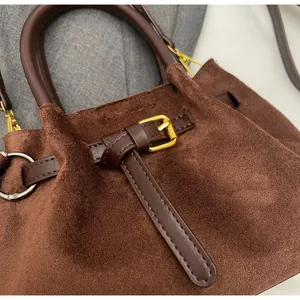 Detalle del bolso saco de ante marrón con correas de cuero y herrajes dorados finos