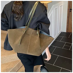 Détail d'un grand sac seau en daim marron avec une bandoulière à nœud élégante à l'épaule
