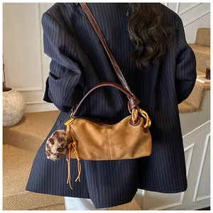 Detail of vintage suede shoulder bag with gold chain and leopard print pom-pom charm