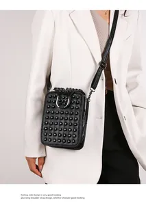 Detail of black studded crossbody bag with adjustable strap on white suit model
