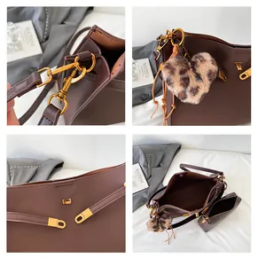 Detalle del bolso de cuero marrón con herrajes dorados y un colgante de peluche