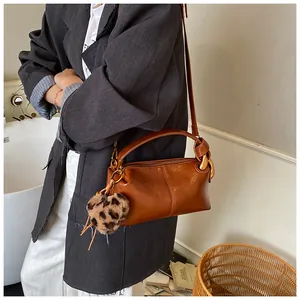 Close-up of brown vintage pillow bag featuring a twisted handle and leopard heart charm