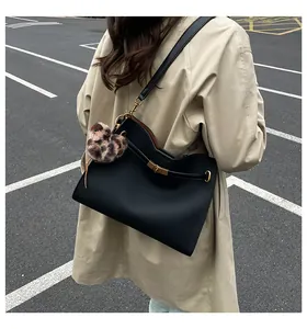 Detalle de bolso Kelly en cuero negro con hebilla dorada y colgante de leopardo