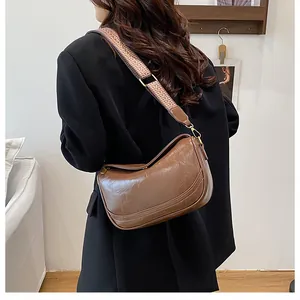 Detail of vintage brown crossbody bag featuring stylish woven wide strap and gold hardware
