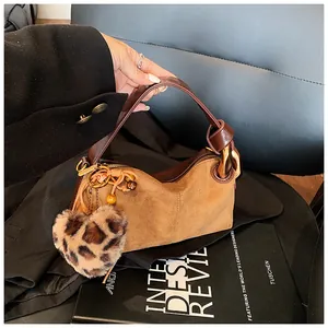 Close-up of brown suede pillow bag with leopard heart charm and gold hardware