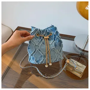 Λεπτομέρεια μπλε denim τσάντα bucket με καπιτονέ υφή και κορδόνι με πέρλες