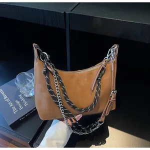 Dettaglio borsa a mezzaluna in camoscio caramello con catena e tracolla in corda intrecciata