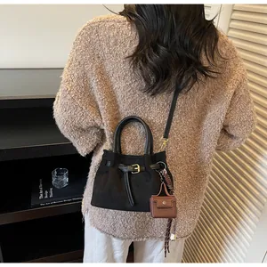 Detalle del bolso de hombro negro mate con correa de hebilla y mini adorno marrón