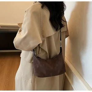 Dettaglio borsa hobo marrone scuro opaco con tracolla in pelle nera e fibbia in metallo