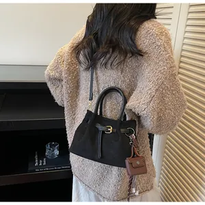 Detalle de bolso cubo negro mate con hebilla, cinta de cuadros y mini funda para cascos